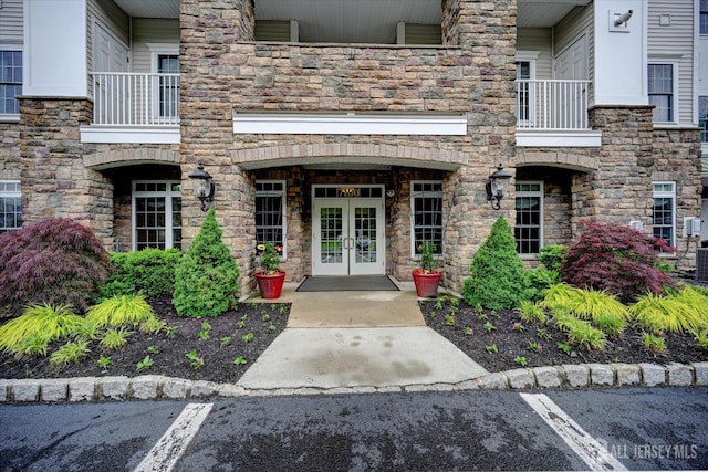 7102 Falston Cir, Old Bridge, NJ 08857 - view of exterior entry with french doors, a balcony, stone siding, and uncovered parking