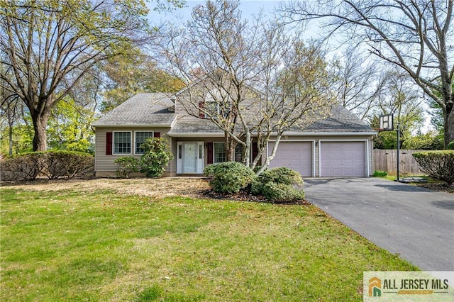 view of front of property with an attached garage, fence, a front yard, and aphalt driveway