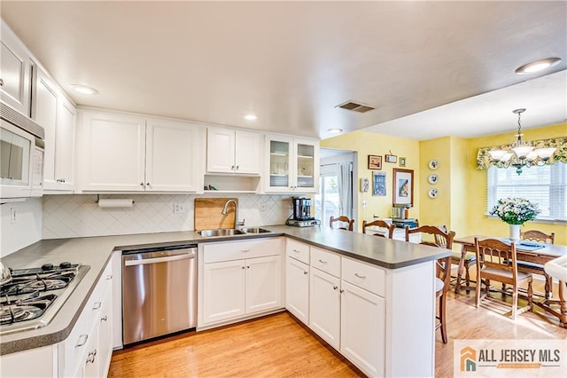 13 Harper Rd, South Brunswick, NJ 08852 - kitchen featuring appliances with stainless steel finishes, a sink, a peninsula, tasteful backsplash, and white cabinetry