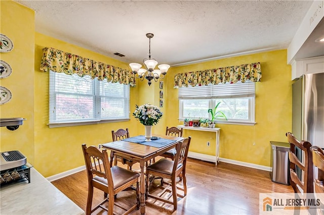 13 Harper Rd, South Brunswick, NJ 08852 - dining space featuring light wood-type flooring, a chandelier, a textured ceiling, and baseboards