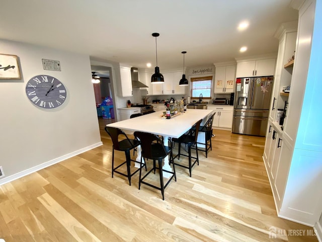 22 E Zoller Rd, East Brunswick, NJ 08816 - kitchen featuring appliances with stainless steel finishes, wall chimney range hood, a sink, white cabinets, and a breakfast bar area