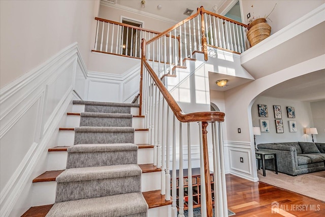 74 Gates Rd, Franklin, NJ 08873 - staircase with wainscoting, wood finished floors, a decorative wall, a high ceiling, and arched walkways