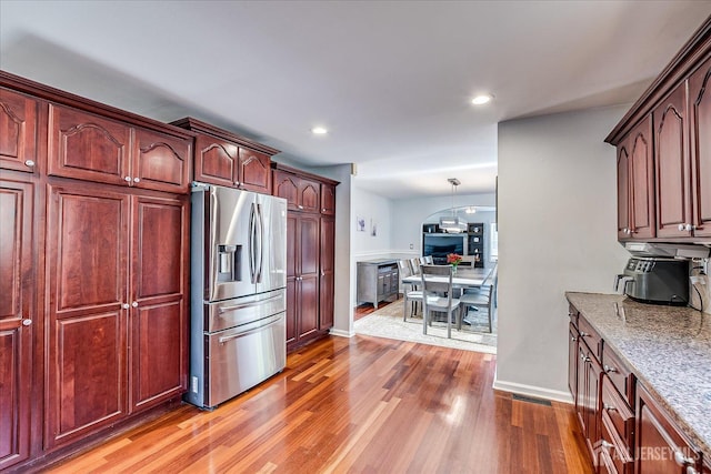 74 Gates Rd, Franklin, NJ 08873 - kitchen featuring stainless steel fridge with ice dispenser, wood finished floors, light stone countertops, recessed lighting, and reddish brown cabinets