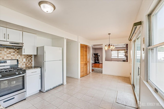 kitchen featuring stainless steel range with gas cooktop, under cabinet range hood, freestanding refrigerator, tasteful backsplash, and white cabinets