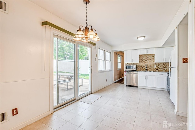 kitchen with stainless steel appliances, a chandelier, tasteful backsplash, white cabinets, and light tile patterned flooring