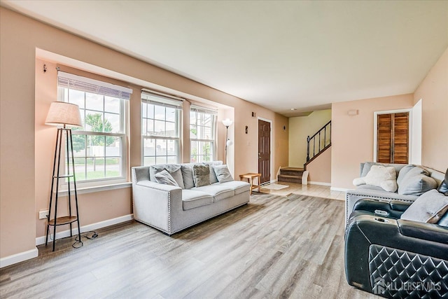 living area with wood finished floors, baseboards, and stairway