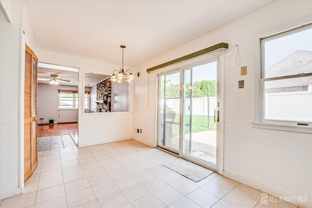 unfurnished dining area featuring light tile patterned floors, a chandelier, baseboards, and a ceiling fan