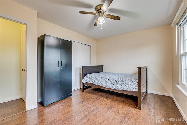 bedroom with wood finished floors, baseboards, a closet, and a ceiling fan