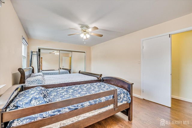 bedroom with light wood-type flooring, baseboards, a ceiling fan, and a closet