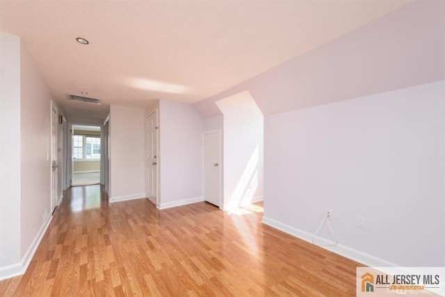 additional living space with baseboards, light wood-type flooring, and visible vents