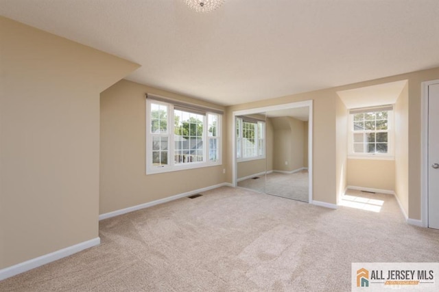 unfurnished bedroom with baseboards, visible vents, and light colored carpet