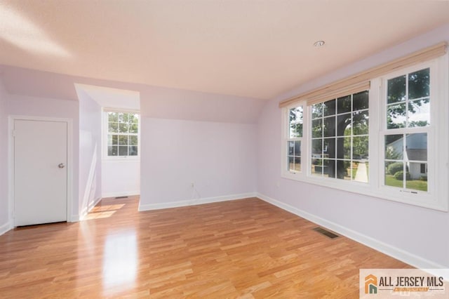 unfurnished room featuring lofted ceiling, baseboards, visible vents, and light wood finished floors