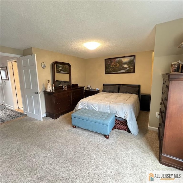 carpeted bedroom featuring a textured ceiling and baseboards