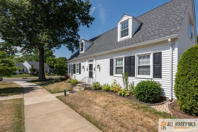 new england style home with a front yard and a shingled roof