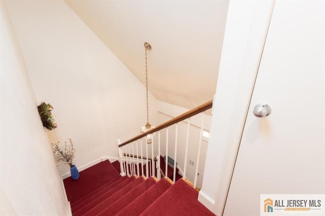 stairs featuring carpet floors, baseboards, and lofted ceiling