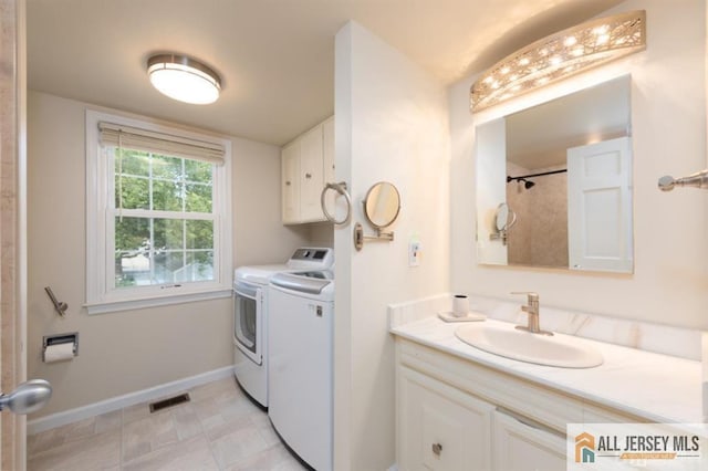 clothes washing area with baseboards, visible vents, laundry area, a sink, and washer and clothes dryer