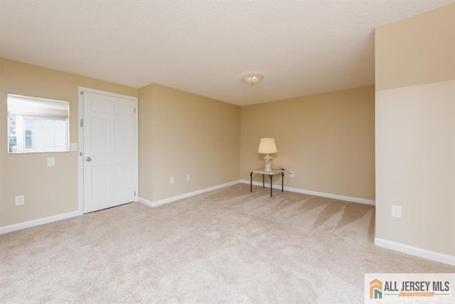 empty room featuring light colored carpet, baseboards, and a textured ceiling