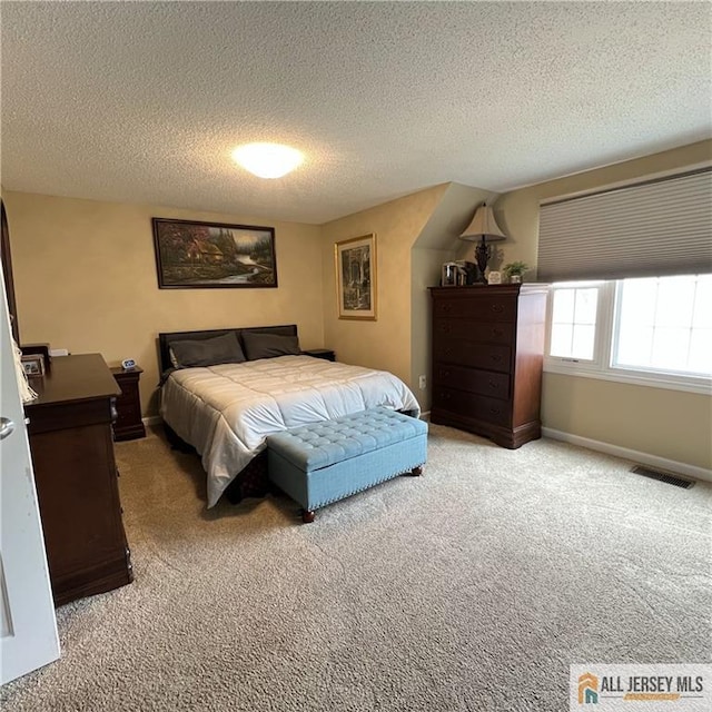 bedroom featuring baseboards, light colored carpet, a textured ceiling, and visible vents