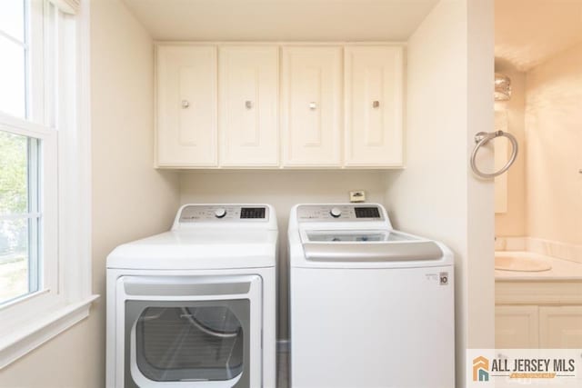 clothes washing area with laundry area, independent washer and dryer, and a sink