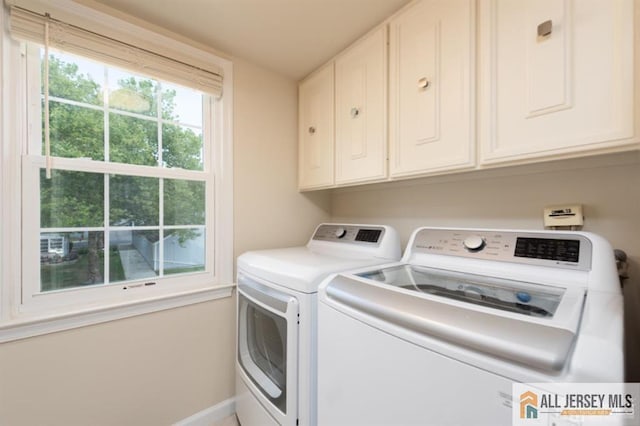 washroom featuring washing machine and clothes dryer, cabinet space, and baseboards