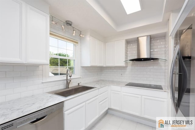 kitchen featuring light stone countertops, white cabinetry, wall chimney exhaust hood, a sink, and stainless steel appliances