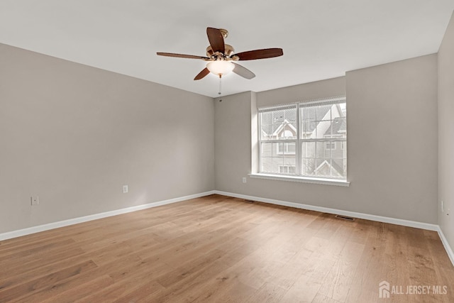 unfurnished room with light wood-style floors, baseboards, visible vents, and a ceiling fan