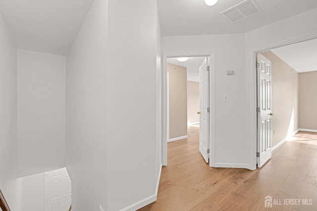 hallway featuring light wood-type flooring, visible vents, and baseboards