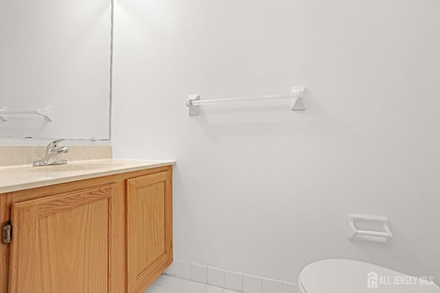 half bath featuring toilet, tile patterned flooring, baseboards, and vanity