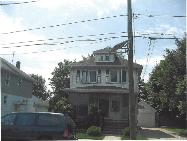 view of front facade featuring an outbuilding, a porch, and a garage