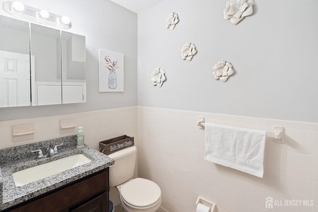 938 Thomas Ave, North Brunswick, NJ 08902 - bathroom featuring toilet, vanity, tile walls, and a wainscoted wall