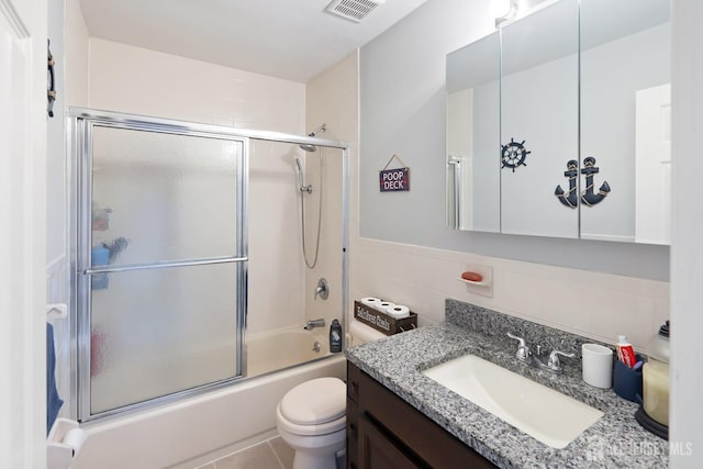 938 Thomas Ave, North Brunswick, NJ 08902 - bathroom featuring vanity, toilet, bath / shower combo with glass door, and tile walls