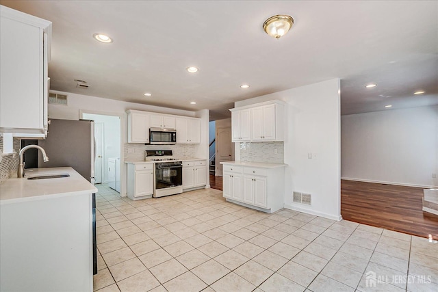 230 S 10th Ave S, Highland Park, NJ 08904 - kitchen with stainless steel appliances, a sink, light tile patterned floors, tasteful backsplash, and light countertops