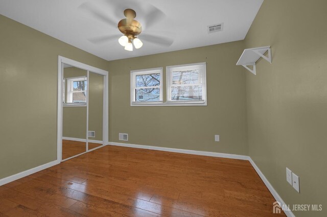 unfurnished bedroom featuring ceiling fan, wood-type flooring, and a closet