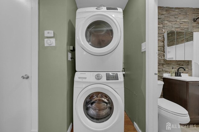 clothes washing area with sink and stacked washer and clothes dryer