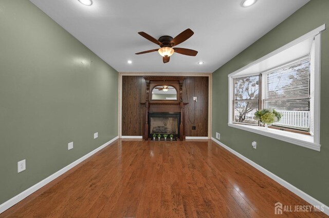 unfurnished living room featuring ceiling fan, wood-type flooring, and a fireplace