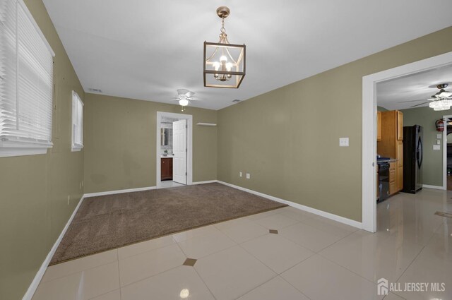 spare room featuring light colored carpet and ceiling fan with notable chandelier