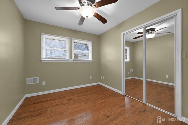 unfurnished bedroom with ceiling fan, wood-type flooring, and a closet