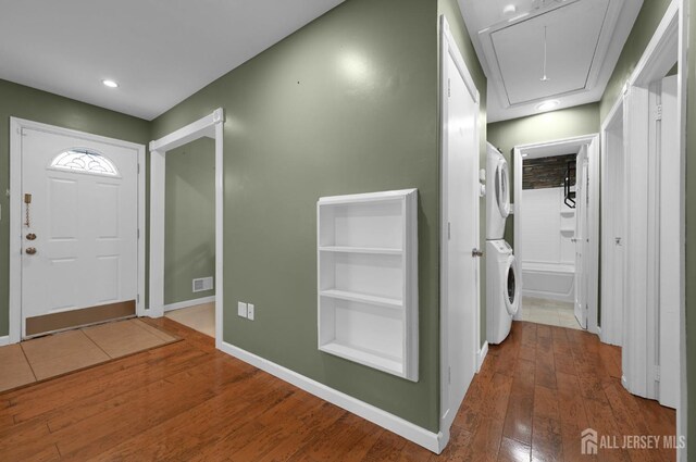 foyer entrance with stacked washer / dryer and hardwood / wood-style floors