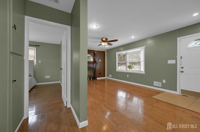 entryway with ceiling fan, a healthy amount of sunlight, wood-type flooring, and a fireplace