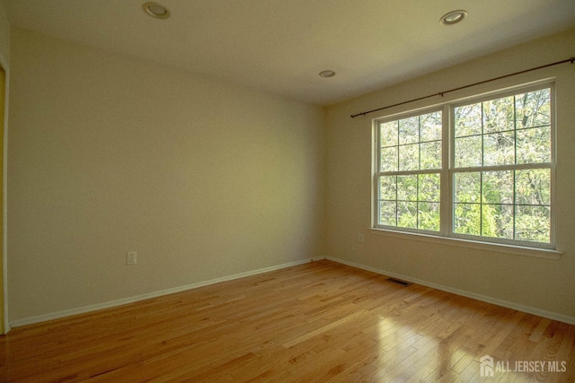 empty room featuring light wood-style flooring, baseboards, and recessed lighting