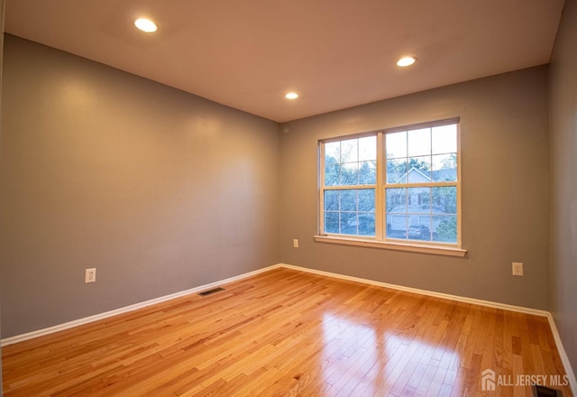 empty room featuring light wood-style floors, baseboards, and recessed lighting