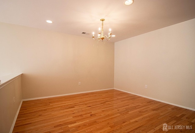 spare room with a chandelier, light wood-style floors, recessed lighting, and baseboards