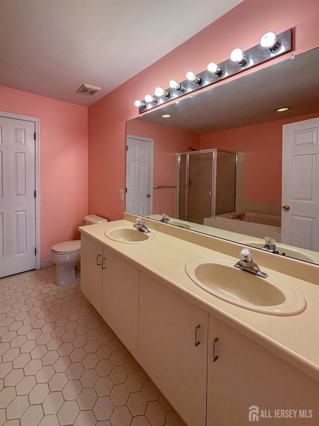 bathroom with a shower stall, double vanity, and toilet