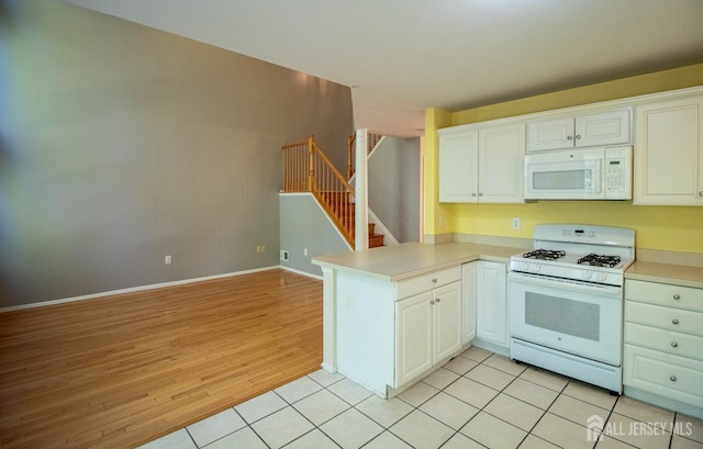 kitchen featuring white appliances, a peninsula, light wood-style floors, and light countertops