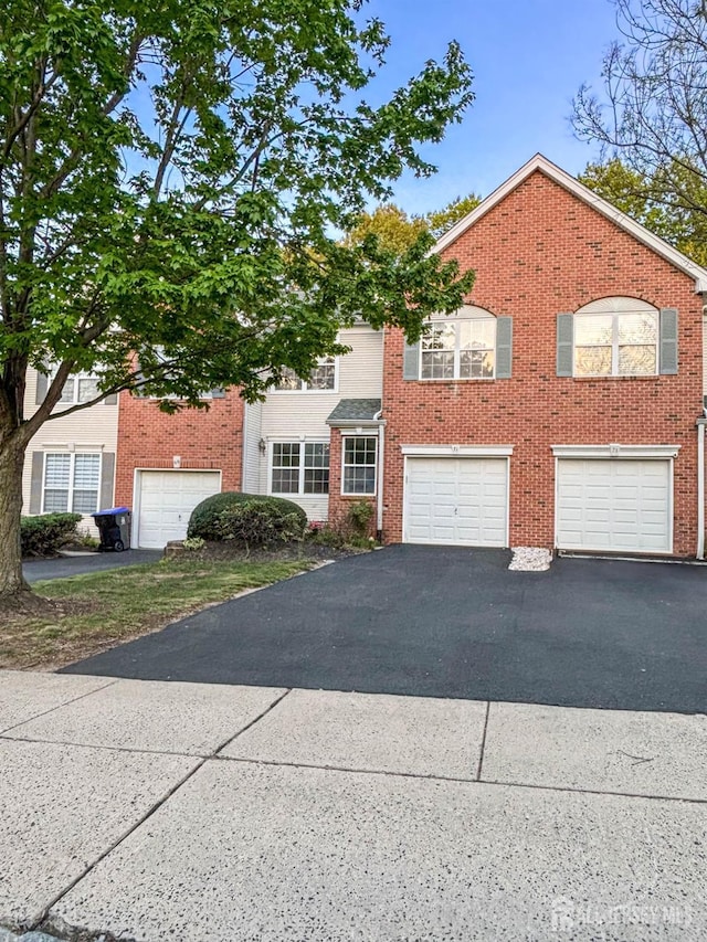 view of front of house featuring asphalt driveway, brick siding, and a garage