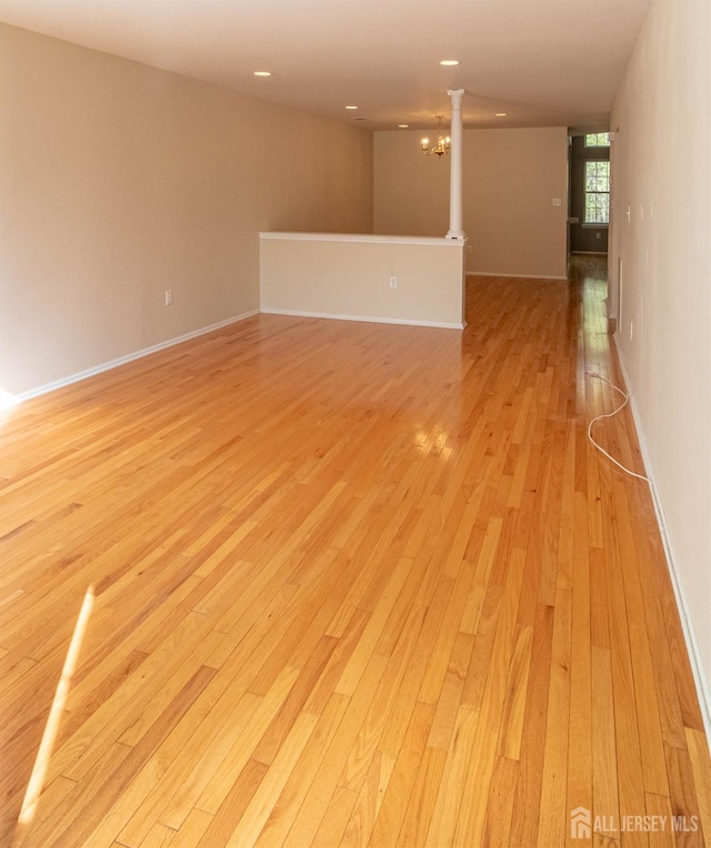 empty room featuring light wood-style flooring, baseboards, a chandelier, and recessed lighting