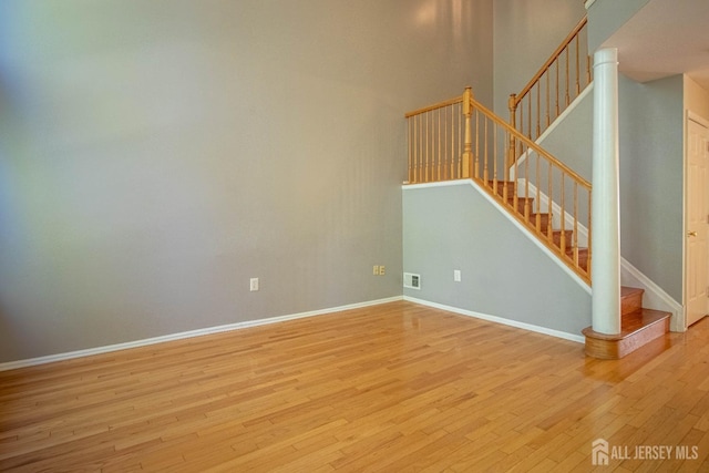 empty room with hardwood / wood-style floors, baseboards, and stairs