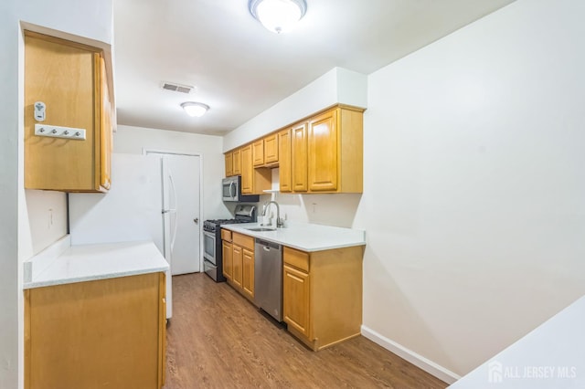 95 Lexington Cir, Old Bridge, NJ 07747 - kitchen featuring stainless steel appliances, a sink, light countertops, and wood finished floors