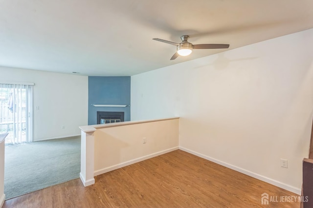 95 Lexington Cir, Old Bridge, NJ 07747 - spare room featuring baseboards, wood finished floors, a glass covered fireplace, and a ceiling fan