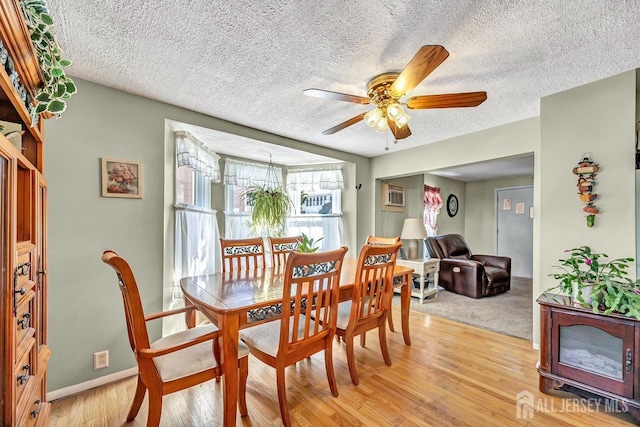 dining space with ceiling fan, an AC wall unit, and light wood-type flooring